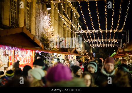 Strasburgo, Francia - Dic 20, 2016: grande folla di gente che passeggia sotto la luce di Natale decorazioni sopra la strada trafficata con bancarelle e chalets vendita di regali Foto Stock