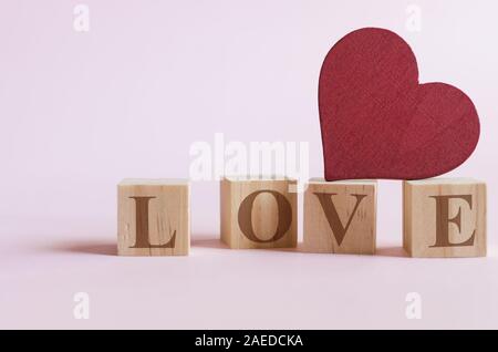 Cuore rosso forma pezzo di legno posto sul cubo di legno con il messaggio di amore Foto Stock