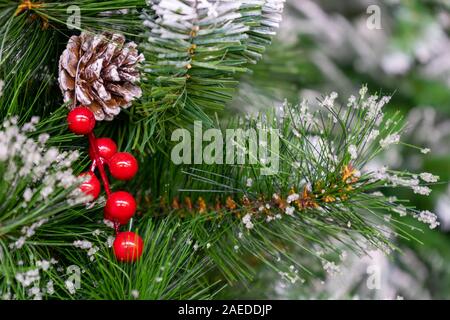 Una chiusura di pigne e bacche rosse su un abete coperto di neve, una tradizionale decorazione di Natale Foto Stock