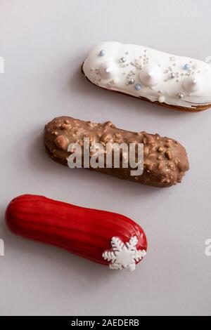 Rosso eclair vetrata con fiocchi di neve bianco su grigio sfondo colorato. Flatlay, overhead, minimalista alimentare il concetto di fotografia. Dolce di Natale Foto Stock