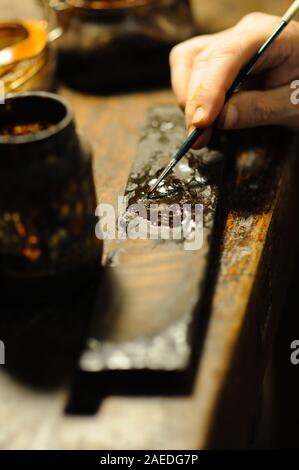 Maestro liutaio che vernicia un liuto a corde di violino fatto a mano come tocchi finali per completare la sua creazione nella sua officina a Cremona, Lombardia Foto Stock