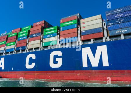 Colorate spedizione cargo contenitori impilati a bordo del francese di portacontainer CMA CGM durante il carico e lo scarico di operazione sotto il cielo blu - Oakla Foto Stock