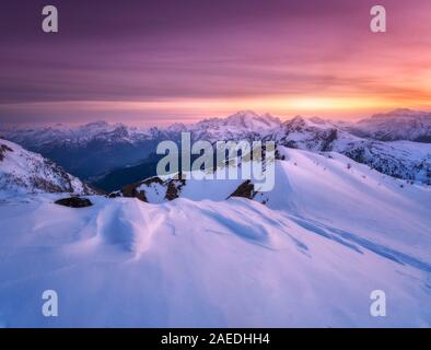 Colorato di rosso il cielo e la luce del sole sopra le montagne coperte di neve Foto Stock