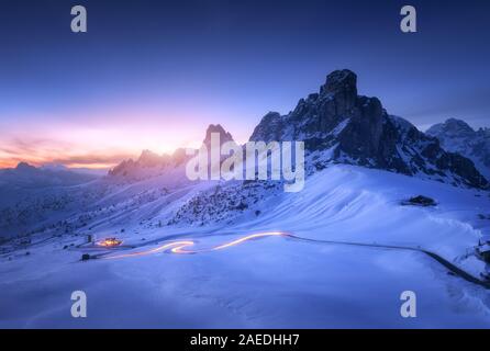 Montagne innevate e sfocata dei fari delle automobili sulla strada tortuosa Foto Stock