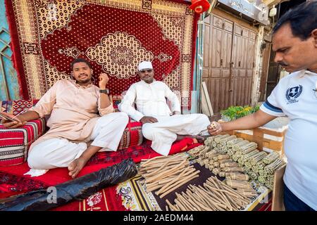 Due uomini arabi vendere miswak pulizia dei denti ramoscelli sull'Souk Baab Makkah street market presso il quartiere storico Al Balad in Jeddah, KSA, Arabia Saudita Foto Stock