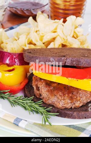Salutari hamburger grigliato in salsa barbecue e servita su tostati Pane pumpernickel. E rabboccato con cotto giallo e peperoni rossi. Foto Stock