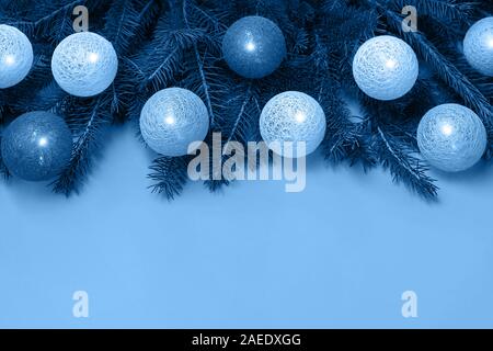 Close up di albero di Natale decorato rami con addobbi di baubles con luci nel quartiere alla moda di colore blu. Colore dell'anno 2020 concept. La piatta Foto Stock