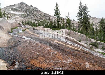 Flusso che scorre verso il basso una lastra di roccia in Idaho Le Sawtooth Mountains. Foto Stock