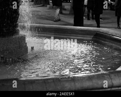 Close-up di fontana e bella riflessione sulla superficie dell'acqua durante la notte a Sloan Square, Londra, Regno Unito. Immagine in bianco e nero. Foto Stock