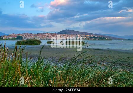 Lago Orestiada e Kastoria city, Grecia al tramonto del tempo. Vista dietro l'erba. Foto Stock