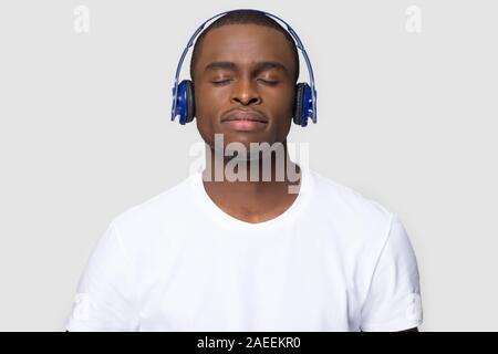 Soddisfatto African American uomo nelle cuffie godendo la musica preferita Foto Stock