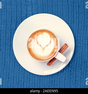 Tazza di caffè o tè chai con latte art virati sul blu. Tempo libero concetto. Colori pastello. Square Foto Stock