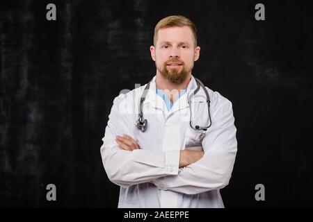 Barbuto giovane medico in camice bianco e phonendoscope oltre il collo Foto Stock