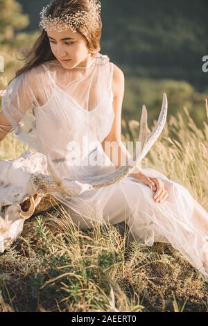 Bellissimo il teschio di cervo con corna, close-up di mano della ragazza giaceva su la testa, natura Foto Stock
