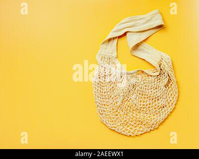 Rifiuti Zero, uno stile di vita sostenibile, plastica libera concetto. Eco Friendly naturale di borsa a rete su sfondo giallo. Vuoto borsa a rete con copia spazio per il testo o il design. Vista superiore o laici piatta Foto Stock