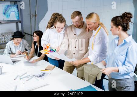 Gruppo di creativi designer di moda a discutere di colori, tessile e schizzi Foto Stock