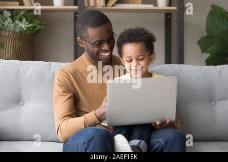 Sorridendo Il papà di colore nero e di piccolo figlio di giocare giochi per computer Foto Stock