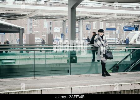 Una giovane donna è in attesa per il treno su una piattaforma ferroviaria a Zwolle stazione ferroviaria di Zwolle, Paesi Bassi Foto Stock