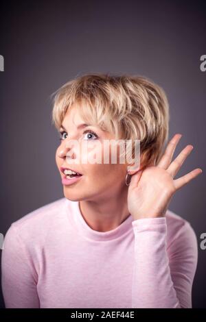 Donna con corti capelli biondi ascoltando il suono. Le persone e le emozioni concetto Foto Stock