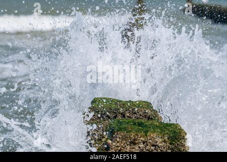 Sea Wave trasferite attraverso una groyne di legno accanto alla spiaggia. Foto Stock