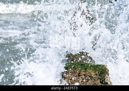 Sea Wave trasferite attraverso una groyne di legno accanto alla spiaggia. Foto Stock