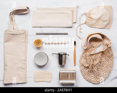 Tessili sacchi eco, metallo cannucce e infusore di tè, eco-friendly utensili per la cucina, spazzolino da denti di bambù e batuffoli di cotone riutilizzabili di tamponi di cotone su marmo bianco dello sfondo. Eco Friendly,rifiuti zero concetto.vista superiore Foto Stock