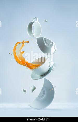 Rotture di tazze da caffè con un tuffo in una composizione di bilanciamento su sfondo bianco Foto Stock