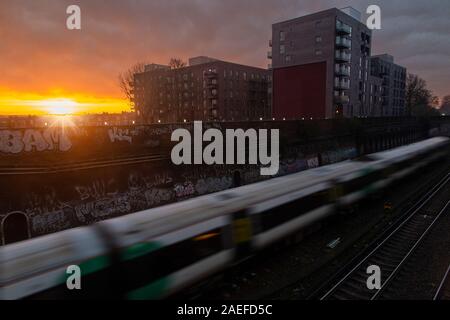 A sud del treno si avvicina Clapham Junction al sorgere del sole Foto Stock