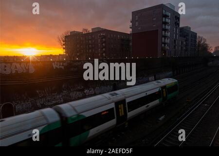 A sud del treno si avvicina Clapham Junction al sorgere del sole Foto Stock