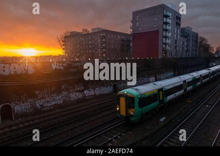 A sud del treno si avvicina Clapham Junction al sorgere del sole Foto Stock