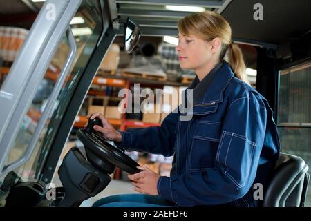 Donna alla guida carrello elevatore in magazzino Foto Stock