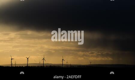 Hannover, Germania. 09Dec, 2019. La ancora bassa sole di mattina e oscura pioggia nuvole forniscono un cielo contrastanti su mulini a vento. Credito: Julian Stratenschulte/dpa/Alamy Live News Foto Stock