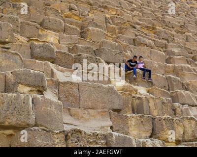 Il Cairo, Egitto - 1 Novembre, 2019: egiziana scuola i bambini seduti sui blocchi della Grande Piramide di Giza. Foto Stock