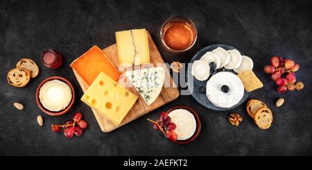 Scheda formaggio panorama con vino e frutta, un piatto di laici che, scattato dalla parte superiore su uno sfondo nero Foto Stock