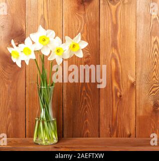 Bouquet di fiori freschi, narcisi in vaso su una tavola di legno, marrone opposta parete in legno. Spazio vuoto per il testo. Foto Stock