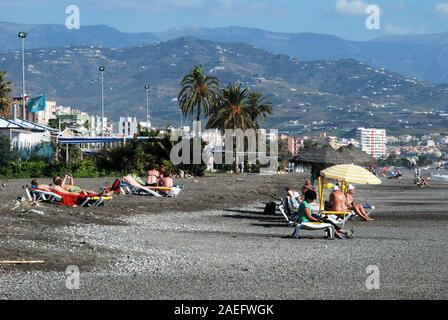I turisti rilassante sulla spiaggia con vista verso la montagna, Torre del Mar, provincia di Malaga, Andalusia, Spagna, Europa occidentale. Foto Stock