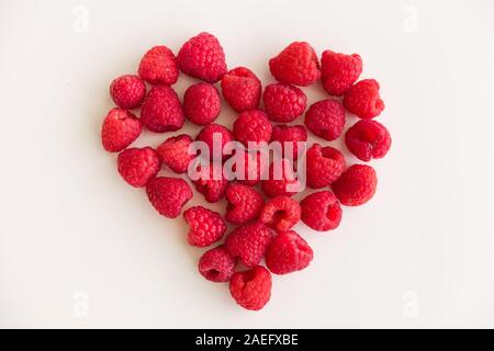 Succosa cuore rosso realizzato di organico dei lamponi freschi su sfondo bianco. Cibo sano per una vita sana. Il giorno di San Valentino Foto Stock