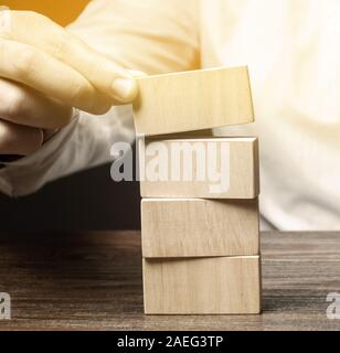 Imprenditore mette i blocchi di legno. Business management concetto. Pianificazione e strategia. Impostazione e raggiungimento degli obiettivi. Stabilità aziendale. Mappa stradale. Foto Stock