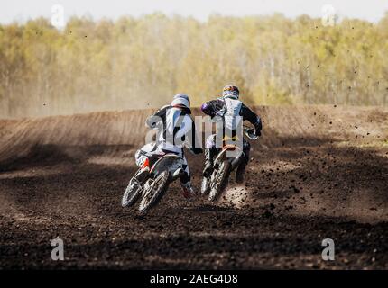 I piloti di motocross sulla pista schizzi di fango da sotto le ruote Foto Stock