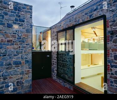 Architettura. Moderno design esterno della casa con pareti di granito e vista attraverso le finestre dell'interno. Foto Stock