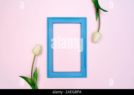 Composizione di fiori. tulip fiori blu con photo frame su sfondo rosa. Appartamento laico, vista dall'alto, spazio di copia Foto Stock