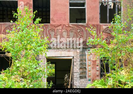 Un vecchio abbandonato scuola sovietica edificio decorato con bassorilievi da simboli sovietica Foto Stock