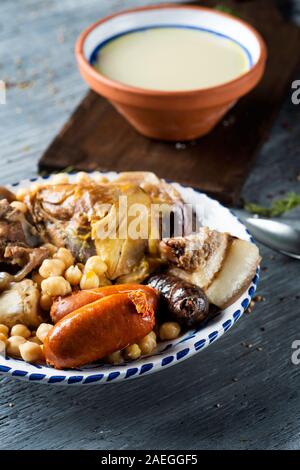 Cocido madrileno, tipico di Madrid, in Spagna, con la Zuppa servita in un recipiente di terracotta e la carne e le verdure utilizzate nel brodo servito in un vassoio Foto Stock