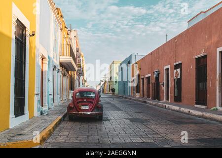 Vecchio rosso Volkswagen maggiolino parcheggiato su una delle vivaci strade della città coloniale di Campeche, Messico. Foto Stock