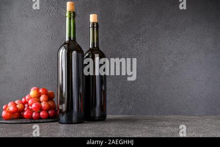 Bottiglie di vino rosso con grappolo di uva laici piatta Foto Stock