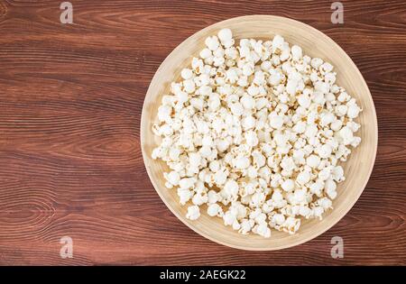 Pop Corn snack nel recipiente, sul tavolo di legno. Vista superiore, banner mockup per il cinema e la tv movie Foto Stock