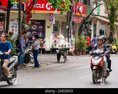 Il vietnamita donna che indossa cappello conico spingendo bicycle & moto, Hanoi, Vietnam Asia Foto Stock