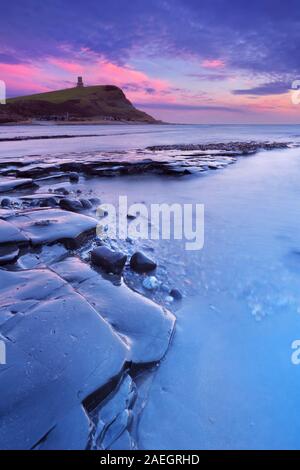 Ultima luce oltre la spiaggia rocciosa di Kimmeridge Bay sulla costa sud dell'Inghilterra. Foto Stock