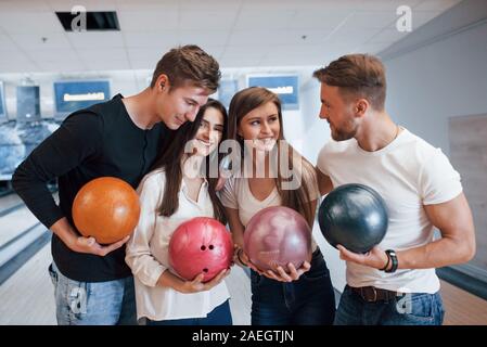 Una conversazione. Giovani amici allegro divertirsi in bowling club presso i loro fine settimana Foto Stock