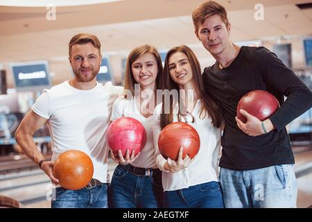 Migliori amici. Giovane gente allegra divertirsi in bowling club presso i loro fine settimana Foto Stock